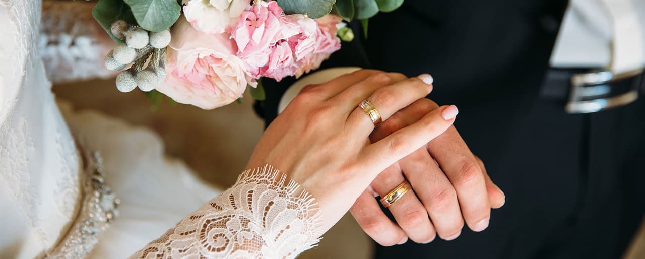 Couple holding hands with wedding rings
